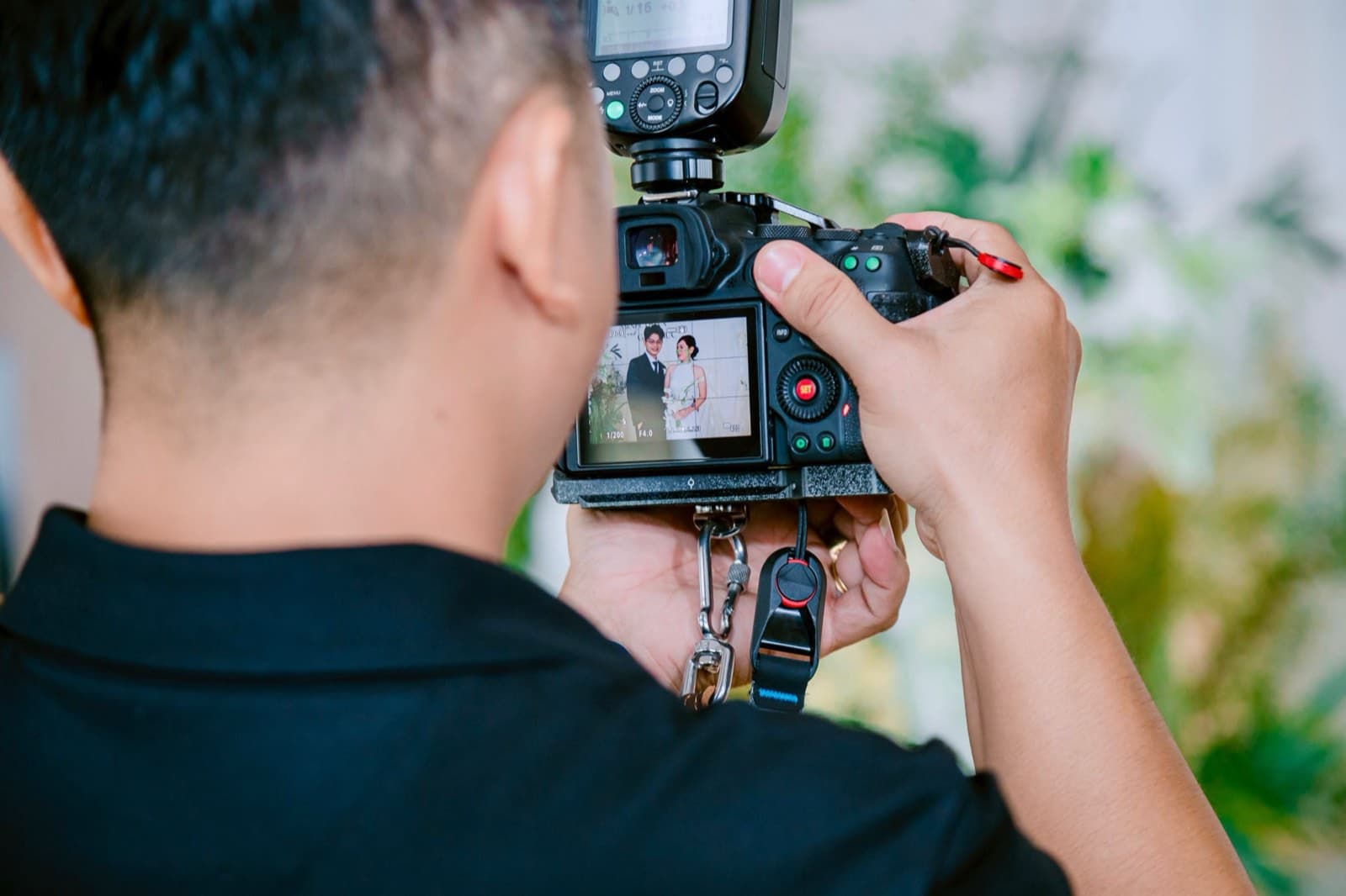 A photographer reviews a portrait of a couple on the camera’s rear screen mid-shoot